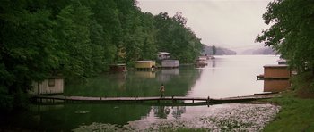 Movie still from “Firestarter” (1984), directed by Mark L. Lester – A man walking across a bridge over a body of water; Extreme Wide shot, High angle