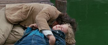 Movie still from “Firestarter” (1984), directed by Mark L. Lester – A man and a woman sleeping on a dock; Medium shot, High angle