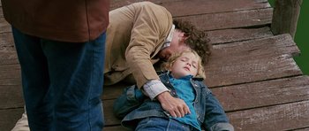 Movie still from “Firestarter” (1984), directed by Mark L. Lester – A man and a little girl laying on the ground; Medium shot, High angle