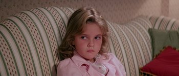 Movie still from “Firestarter” (1984), directed by Mark L. Lester – A little girl sitting on top of a striped couch; Close Up shot, High angle