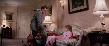 Movie still from “Firestarter” (1984), directed by Mark L. Lester – A man and a little girl sitting on a couch in a living room; Wide shot, Over the shoulder angle