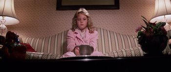 Movie still from “Firestarter” (1984), directed by Mark L. Lester – A little girl sitting on top of a striped couch; Medium shot, High angle