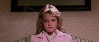 Movie still from “Firestarter” (1984), directed by Mark L. Lester – A young girl in a pink coat looking at the camera; Close Up shot, Low angle
