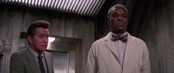 Movie still from “Firestarter” (1984), directed by Mark L. Lester – A man wearing a white suit and a bow tie; Close Up shot, Low angle