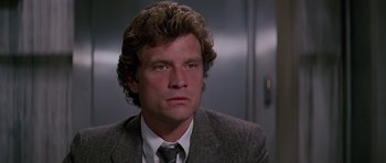 Movie still from “Firestarter” (1984), directed by Mark L. Lester – A person wearing a suit and tie; Close Up shot, Low angle