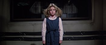 Movie still from “Firestarter” (1984), directed by Mark L. Lester – A young girl standing in front of a wall; Medium shot, Low angle