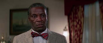 Movie still from “Firestarter” (1984), directed by Mark L. Lester – An older man wearing a suit and a bow tie; Close Up shot, Low angle