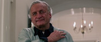 Movie still from “Firestarter” (1984), directed by Mark L. Lester – An older man with grey hair is holding his hand on his chest; Close Up shot, Low angle