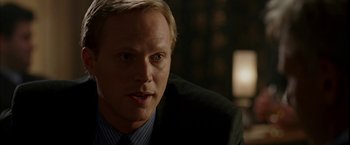 Movie still from “Firewall” (2006), directed by Richard Loncraine – A man in a suit and tie sitting in a room; Close Up shot, Over the shoulder angle