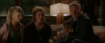 Movie still from “Firewall” (2006), directed by Richard Loncraine – A man and a woman sitting on a couch with a child; Medium shot, Over the shoulder angle