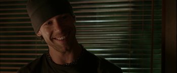 Movie still from “Firewall” (2006), directed by Richard Loncraine – A man smiling for the camera in front of blinds; Close Up shot, Over the shoulder angle