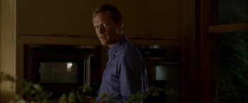 Movie still from “Firewall” (2006), directed by Richard Loncraine – A man standing in a kitchen wearing a dress shirt; Close Up shot, Low angle