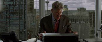 Movie still from “Firewall” (2006), directed by Richard Loncraine – A man in a suit and red tie looking at a laptop computer; Medium shot, Low angle