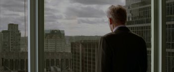 Movie still from “Firewall” (2006), directed by Richard Loncraine – A man in a suit looking out over a city skyline; Medium shot, Over the shoulder angle