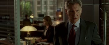 Movie still from “Firewall” (2006), directed by Richard Loncraine – A man in a business suit and a woman in a business suit; Medium shot, Over the shoulder angle