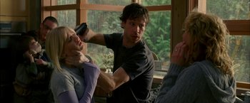 Movie still from “Firewall” (2006), directed by Richard Loncraine – A young man is combing a woman's hair in front of a window; Medium shot, Over the shoulder angle