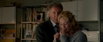 Movie still from “Firewall” (2006), directed by Richard Loncraine – A man and a woman in a room with a bookshelf in the background; Close Up shot, Low angle