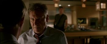 Movie still from “Firewall” (2006), directed by Richard Loncraine – A man with a red tie standing next to another man in a kitchen; Close Up shot, Over the shoulder angle