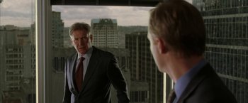 Movie still from “Firewall” (2006), directed by Richard Loncraine – A man standing in front of a mirror in front of a building; Medium shot, Over the shoulder angle