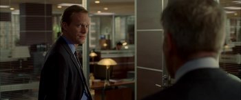 Movie still from “Firewall” (2006), directed by Richard Loncraine – A man in a suit standing in front of a mirror; Medium shot, Over the shoulder angle