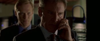 Movie still from “Firewall” (2006), directed by Richard Loncraine – A man in a business suit talking on a phone; Close Up shot, Low angle