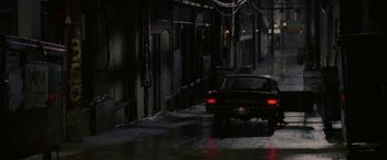 Movie still from “Firewall” (2006), directed by Richard Loncraine – A car is driving down the street at night; Extreme Wide shot, High angle