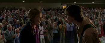 Movie still from “Firewall” (2006), directed by Richard Loncraine – A couple of people standing next to each other in front of a crowd; Close Up shot, Over the shoulder angle