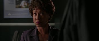 Movie still from “Firewall” (2006), directed by Richard Loncraine – A woman with short hair is standing in a dark room; Close Up shot, Over the shoulder angle