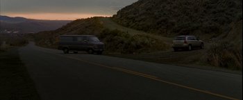 Movie still from “Firewall” (2006), directed by Richard Loncraine – A van driving down a road next to a hill; Extreme Wide shot, Low angle