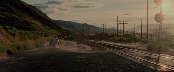 Movie still from “Firewall” (2006), directed by Richard Loncraine – A car driving down a road next to train tracks; Extreme Wide shot, High angle