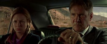 Movie still from “Firewall” (2006), directed by Richard Loncraine – Two people in a car driving on a road; Close Up shot, Over the shoulder angle