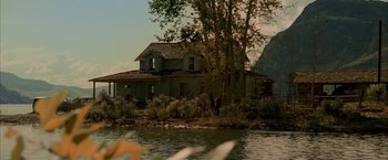 Movie still from “Firewall” (2006), directed by Richard Loncraine – An old house sitting next to a body of water; Extreme Wide shot, Low angle
