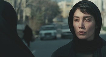 A woman in a black hooded jacket standing on the side of the street