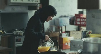 A woman pouring orange juice into a pitcher