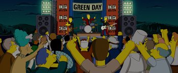 Movie still from “The Simpsons Movie” (2007), directed by David Silverman – A group of people that are sitting in front of a stage; Wide shot, High angle