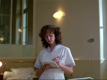 Movie still from “First Name: Carmen” (1983), directed by Jean-Luc Godard – A woman in a white uniform writing on a tablet; Medium shot, Low angle