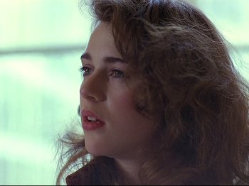 Movie still from “First Name: Carmen” (1983), directed by Jean-Luc Godard – A person with long brown hair; Close Up shot, Over the shoulder angle