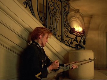 Movie still from “First Name: Carmen” (1983), directed by Jean-Luc Godard – A man in a uniform holding a rifle; Medium shot, Low angle