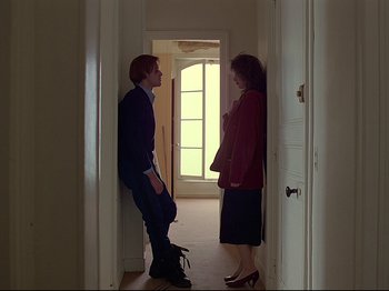 Movie still from “First Name: Carmen” (1983), directed by Jean-Luc Godard – A man and a woman standing in a doorway; Wide shot, Low angle