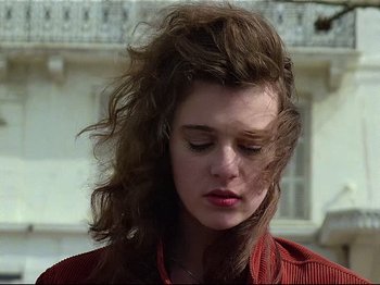 Movie still from “First Name: Carmen” (1983), directed by Jean-Luc Godard – A young woman with long brown hair is looking down at her face; Close Up shot, Low angle