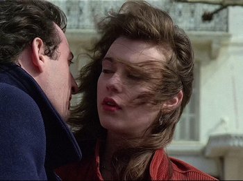 Movie still from “First Name: Carmen” (1983), directed by Jean-Luc Godard – A man and a woman kissing in front of a building; Close Up shot, Low angle
