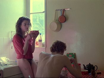 Movie still from “First Name: Carmen” (1983), directed by Jean-Luc Godard – A woman standing next to a man in a kitchen; Medium shot, Low angle