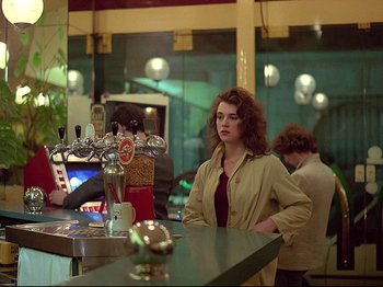 Movie still from “First Name: Carmen” (1983), directed by Jean-Luc Godard – A woman standing at the bar of a restaurant; Medium shot, Over the shoulder angle