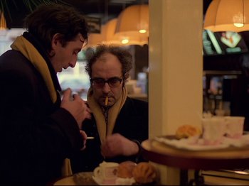 Movie still from “First Name: Carmen” (1983), directed by Jean-Luc Godard – Two men are talking at a table in a restaurant; Medium shot, Over the shoulder angle