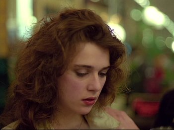Movie still from “First Name: Carmen” (1983), directed by Jean-Luc Godard – A person with curly brown hair; Close Up shot, Over the shoulder angle