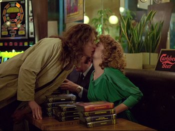 Movie still from “First Name: Carmen” (1983), directed by Jean-Luc Godard – A couple of people sitting at a table kissing each other; Medium shot, Over the shoulder angle