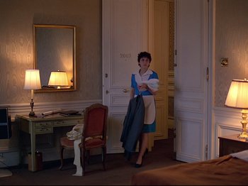 Movie still from “First Name: Carmen” (1983), directed by Jean-Luc Godard – A woman in a blue dress holding a suit jacket; Wide shot, High angle