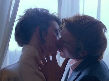 Movie still from “First Name: Carmen” (1983), directed by Jean-Luc Godard – A man and a woman kissing in front of a window; Close Up shot, Over the shoulder angle
