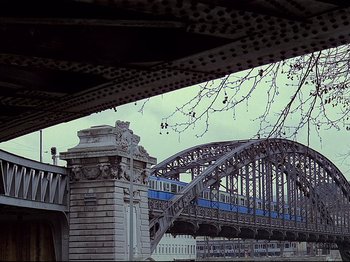 Movie still from “First Name: Carmen” (1983), directed by Jean-Luc Godard – A train is going over a bridge in a city; Extreme Wide shot, Low angle