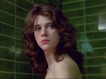 Movie still from “First Name: Carmen” (1983), directed by Jean-Luc Godard – A woman with long brown curly hair posing for a picture; Close Up shot, Low angle